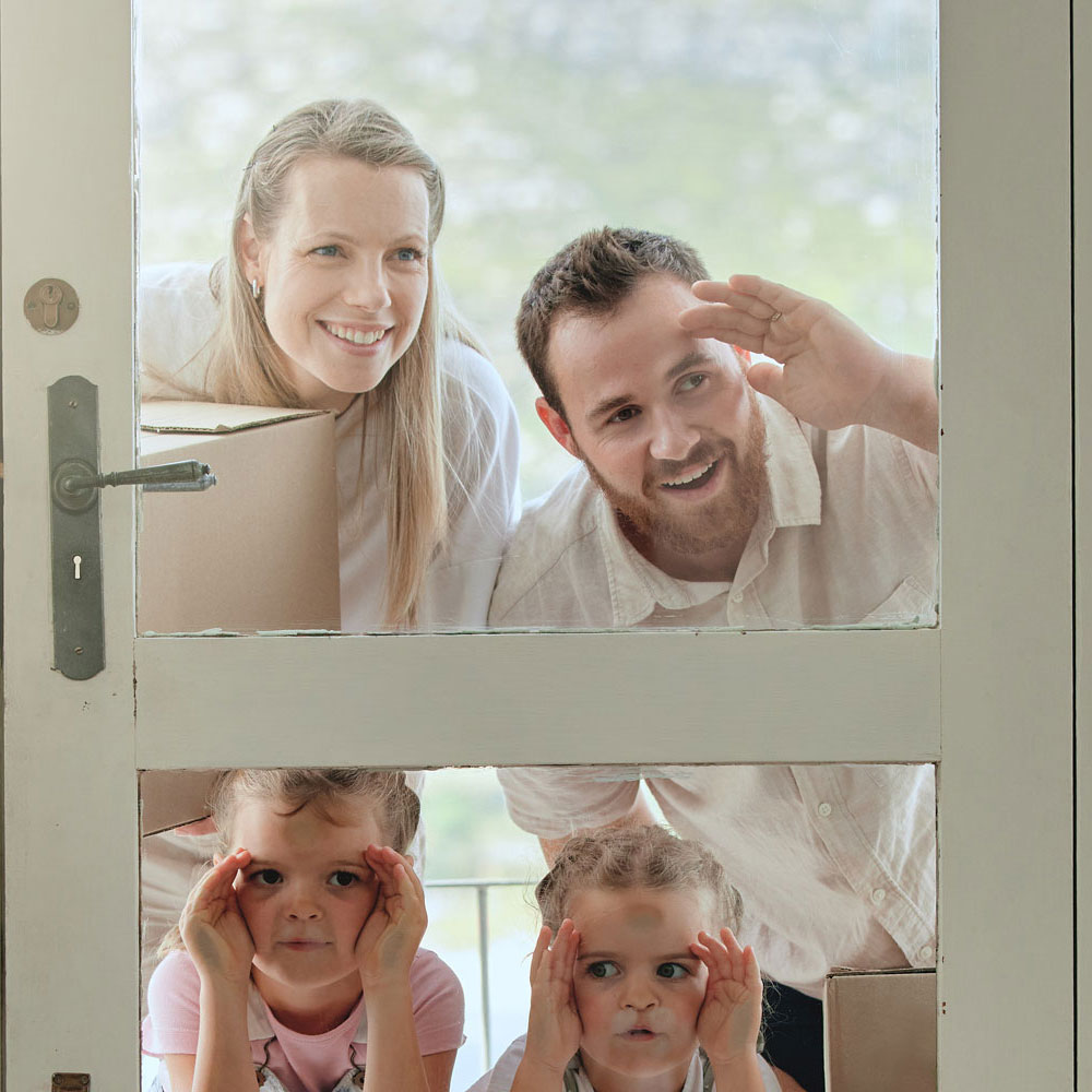 gezin, vader, moeder en twee kinderen kijken door een glazen deur naar binnen
